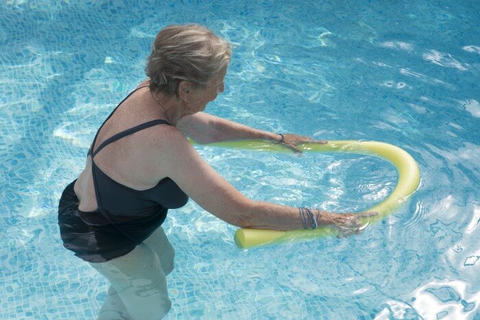 Senhora em piscina praticando hidroginástica